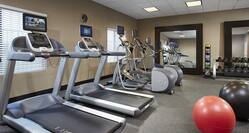 Fitness Center With Cardio Equipment Facing Windows, Two Large Mirrors, Weight Balls, Free Weights, and Two Exercise Balls