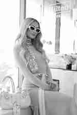 Seorang wanita duduk dengan gaun merah muda