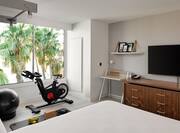 Bed in room with TV and exercise equipment