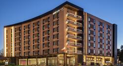 Stunning modern Home2 Suites hotel exterior featuring glowing lights, spacious patio, and dusk sky.