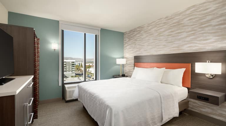 Bright private bedroom in suite featuring TV, comfortable king bed, and stunning outside view.