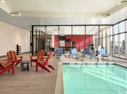 Stunning indoor swimming pool featuring floor to ceiling windows and ample seating,.