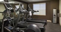 Cardio Equipment Facing Mirrored Wall and Water Cooler in Fitness Center