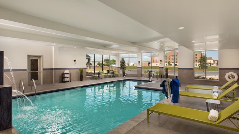 Indoor Pool With Windows, Tables, Chairs, and Loungers