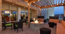 Armchairs With Green Cushions and Striped Sofas by Round Fire Pit on Illuminated Outdoor Patio at Night