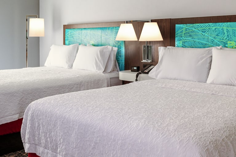 Une chambre d’un hôtel Hampton avec deux grands lit l'un à côté de l'autre. 