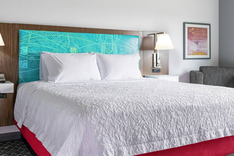 Un letto king size e una sedia in una camera di un Hampton by Hilton. 