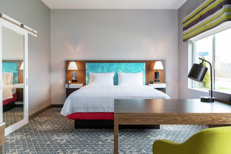 Eine große Suite mit Kingsize-Bett, Schreibtisch und Stuhl in einem Hampton by Hilton Hotel. 