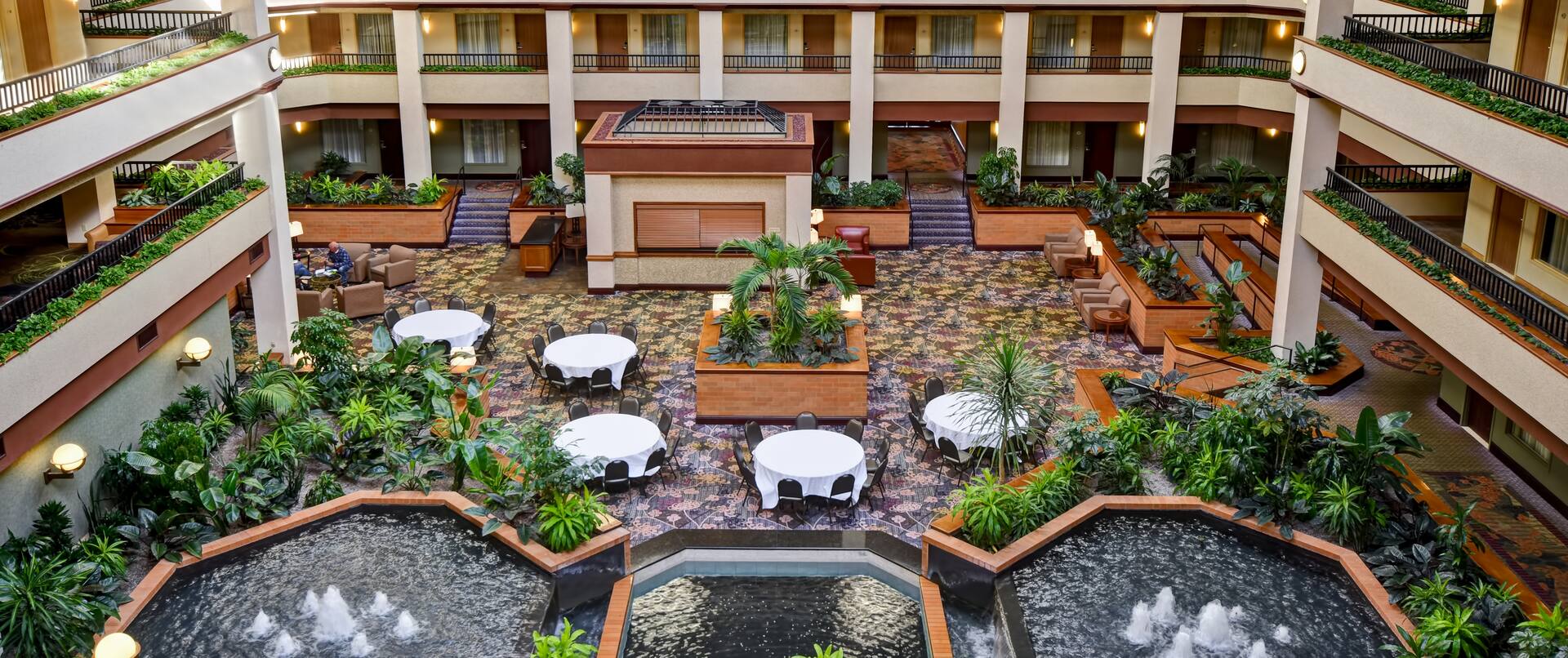 overview of hotel atrium, dining tables, water fountains
