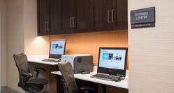 On-Site Business Center With Signage, Overhead Cabinets, Two Computer Workstations, Ergonomic Chairs, and Printer