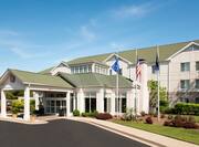 Diagonal View of Hotel Exterior, Entrance Driveway, Landscaping, and Flagpoles