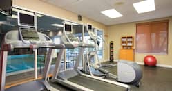 Fitness Center With TV, Cardio Equipment Facing Windows With View of Indoor Pool, Weight Balls, Towel Station and Red Exercise Ball,