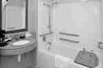 Bak Mandi dengan Kursi dan Grab Bar di Kamar Tamu Ramah Penyandang Disabilitas