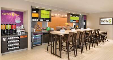 Hot Beverage Station, Hot and Cold Breakfast Options in Food Service Area With TV and Counter Seating