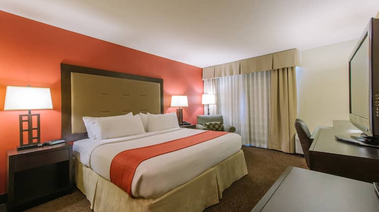 King bedroom with TV and chair in room corner