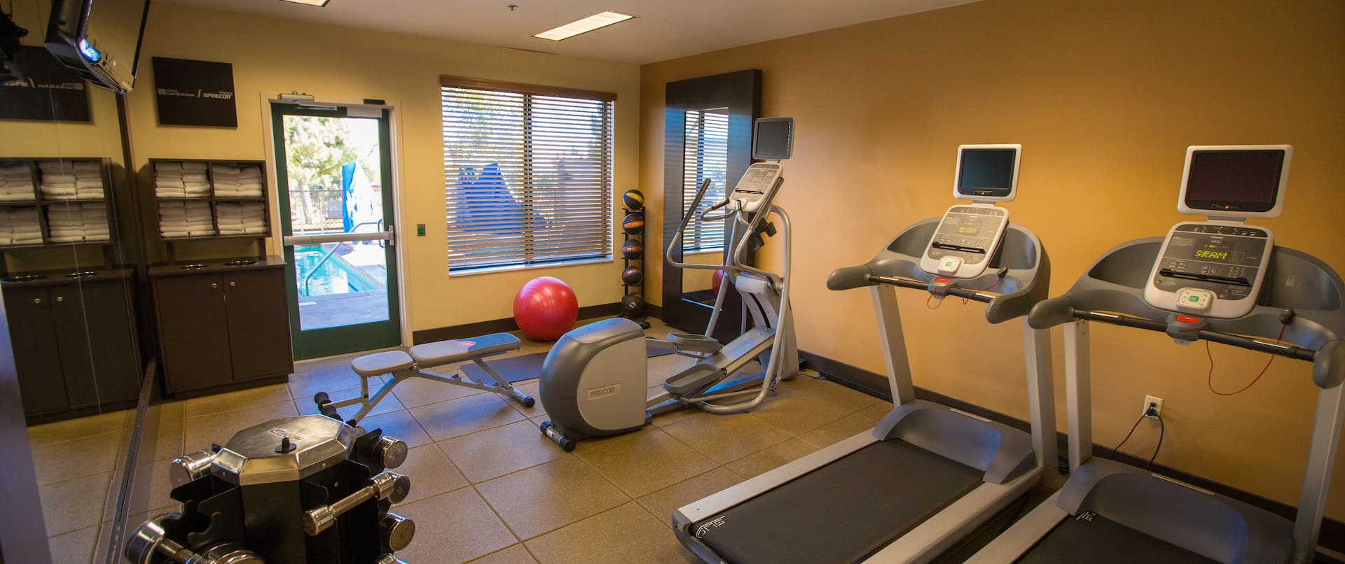 Fitness Center With Cardio Equipment, Free Weights, TV, Towel Station, Weight Bench, Exercise Ball, Weight Balls, and Mirror