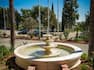 Garden Fountain in Front of Three Flagpoles by Cars on Parking Lot