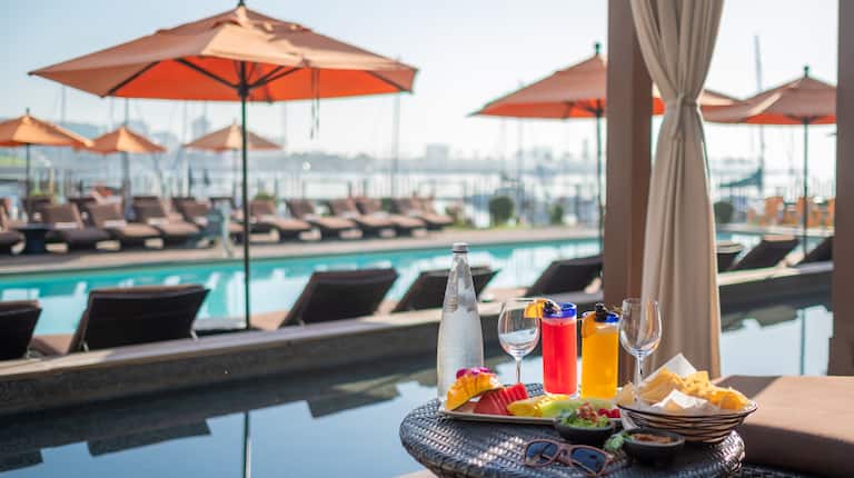 snacks, fruit plate and drinks on a table by the outdoor pool