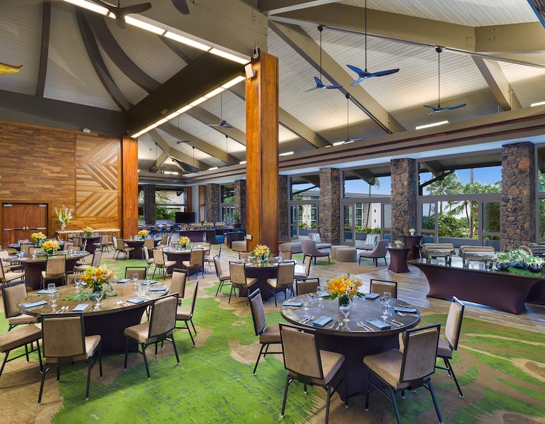 Kuhio Ballroom With Ceiling Fans, Round Tables and Chairs, Large Windows, and Lounge Area in Background