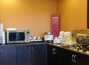 Breakfast serving area with buffet tray, microwave, oatmeal, and pastries