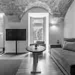 منطقة صالة في غرفة بها أريكة، وطاولة خشبية مستديرة، ومقعد، وتلفزيون 