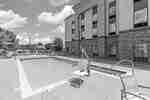 Outdoor pool with tables and chairs protected by sun umbrellas.