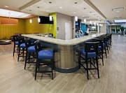Bar With Blue Chairs at Counter, TV, and Lounge Area With Silver Table and Soft Seating