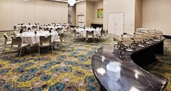 Round Tables Decorated With White Tablecloths and Food Service Table Set Up in Meeting Room