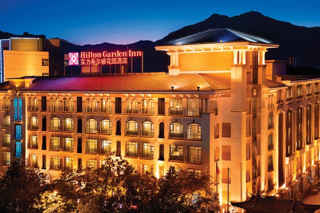 Aerial Overvieow of Hotel Exterior, Signage, Flag Poles, and Landscaping Illuminated at Night