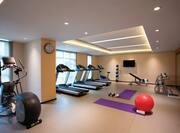Fitness Center With Cardio Equipment Facing Large Windows, Weight Machines, TV by Large Mirror, and Water Cooler