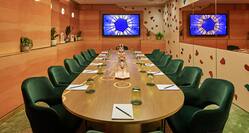 Agora meeting room with large table and 14 green chairs, distinct blue star wall art
