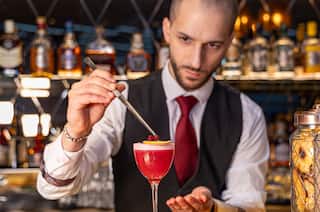 Bar staff preparing cocktail, placing fruit on top