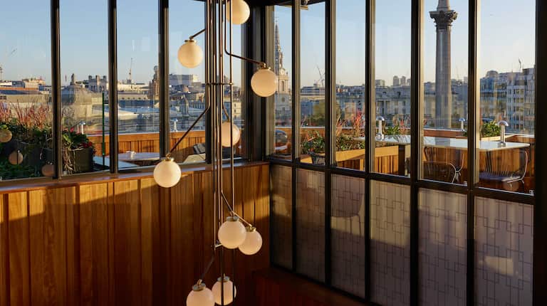 Light chandelier in Rooftop restaurant stairway entrance, with view of city through high windows 