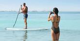 a woman taking a photo of a man on a paddle board