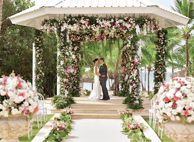 a bride and groom standing under a wedding gazebo