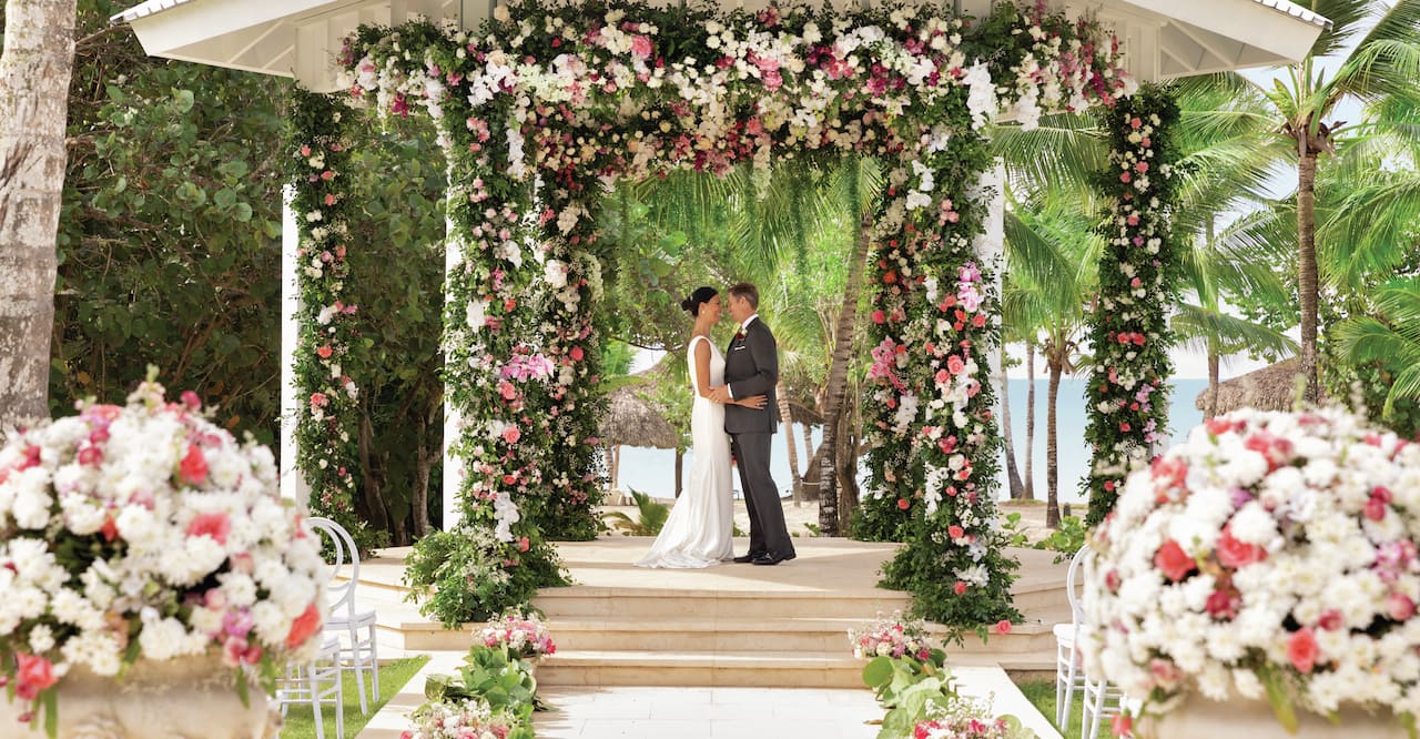 a bride and groom standing under a wedding gazebo