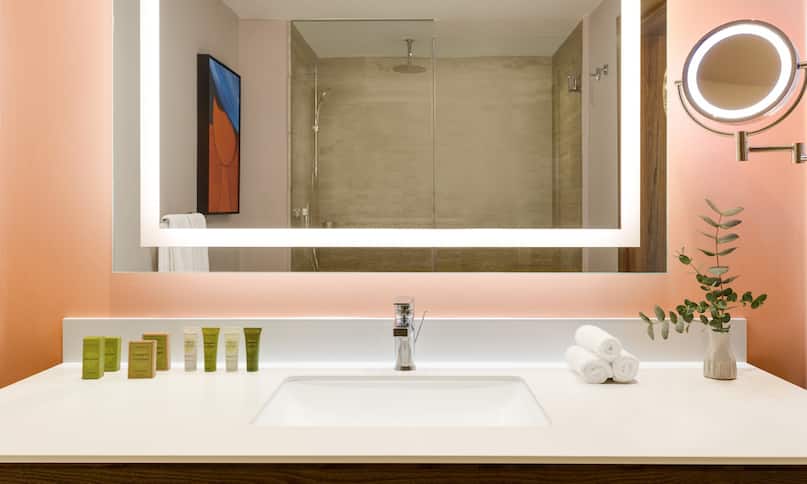 Vanity Area with Lit Mirror and Amenities in Hotel Guest Room-previous-transition