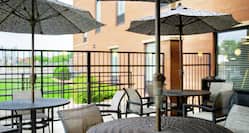 Patio Tables with Umbrellas and Chairs on Lower Level of Outdoor Terrace
