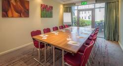 Boardroom Table With Seating for 10, Wall Art, and Presentation Easel in Corner by Glass Door in Harpenden Suite