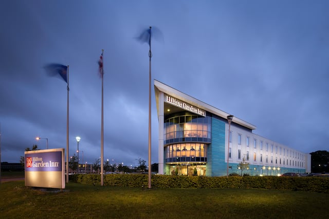 Illuminated Hotel Exterior, Signage, Flag Poles, and Landscaping at Dusk