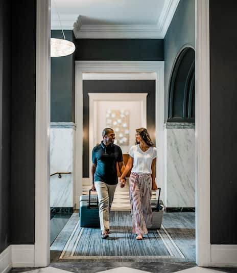 Man and woman walking through hotel holding hands
