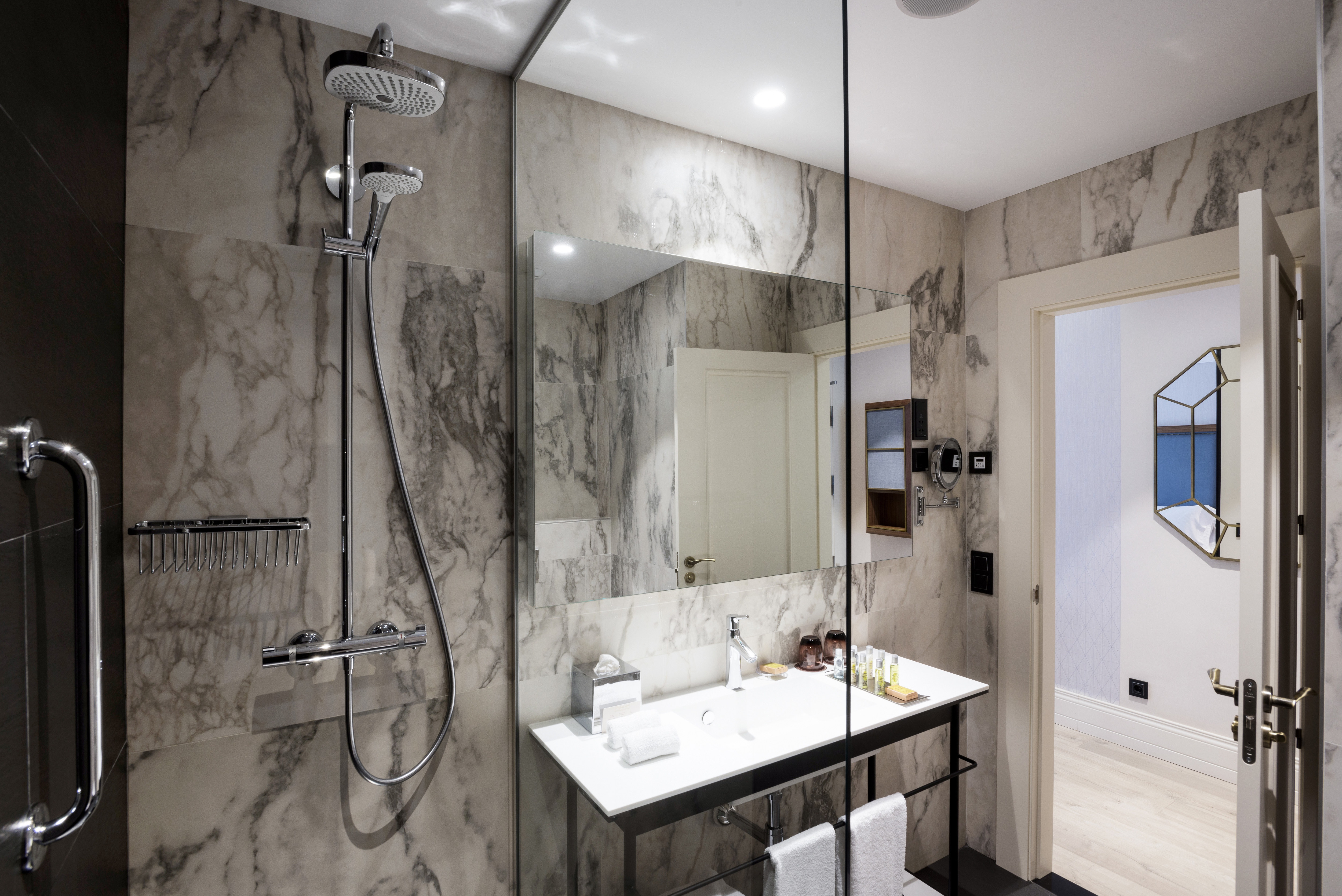 Shower With Glass Doors, Large Vanity Mirror, Sink, Fresh Towels, and Toiletries in Superior Bathroom With Open Doorway to Bedroom