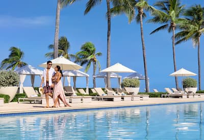 Couple walking by pool at Hilton Rose Hall, an all-inclusive resort. 