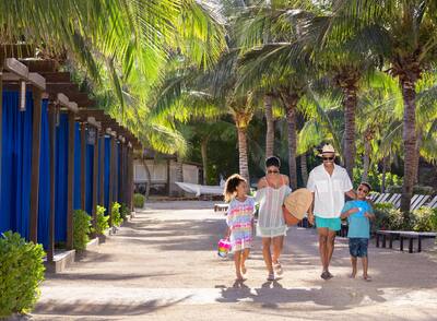 Family of four walking by the cabanas at Hilton Rose Hall Resort & Spa, an all-inclusive resort.