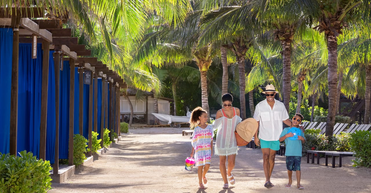 Family of four walking by the cabanas at Hilton Rose Hall Resort & Spa, an all-inclusive resort.