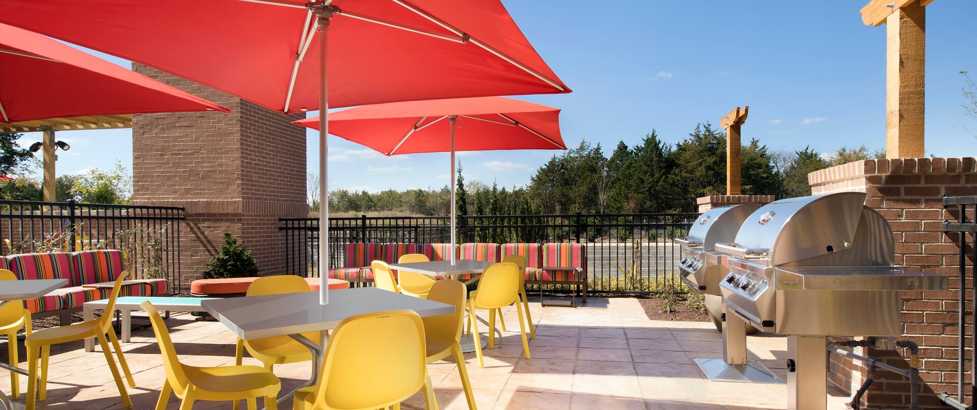 Outdoor patio with grills and seating area with tables, chairs and parasols