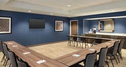 Spacious on-site meeting room fully set with large u shape tables, TV, and refreshment station.