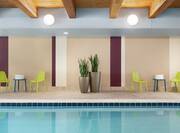 Indoor pool with beautiful wood ceiling, complimentary towels, ample seating and lush green plants.