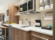 Spacious studio suite featuring fully equipped kitchen, work desk with ergonomic chair, and TV.