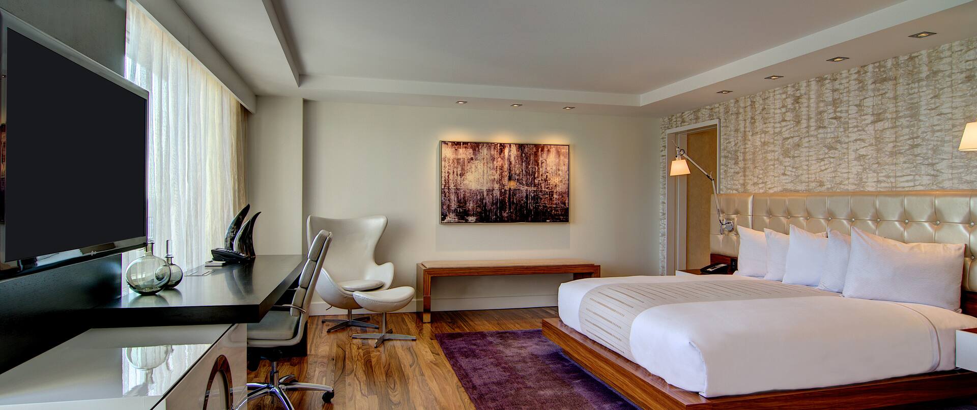 Suite Bedroom with bed on area rug, facing TV and work desk